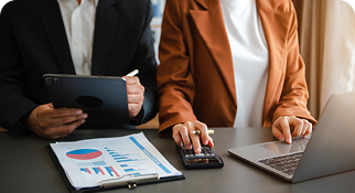Professionals reviewing financial data using a tablet, laptop, and calculator during a business meeting.