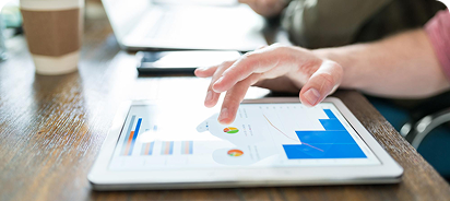Hands interacting with a tablet displaying data charts and digital performance metrics.