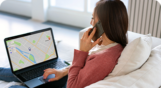 Remote professional using a laptop and mobile phone with a digital map displayed on screen.
