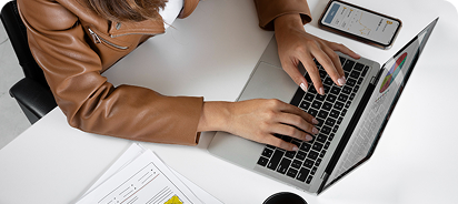 Professional working on a laptop analyzing website data and digital strategy documents.