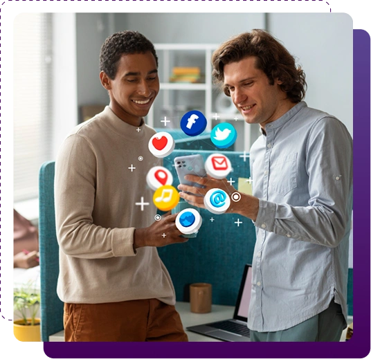 Two smiling young men standing side by side in an office, each holding a smartphone with colorful 3D social media icons (Facebook blue F, Twitter bird, red heart, green WhatsApp, music note, envelope, Google pin, blue bubble) floating around the phones against a modern blue office background with shelves and a laptop.