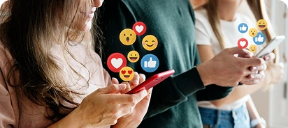 Three people standing close together, each holding a smartphone and looking at their screens, with floating social media reaction icons (hearts, likes, emojis) above their devices.